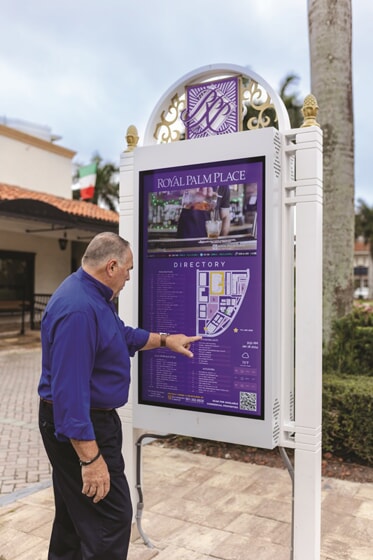 An image of a man looking at a purple directional sign with a map of the area.
